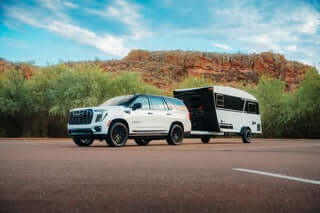 SUV towing a travel trailer on a road with desert landscape in the background