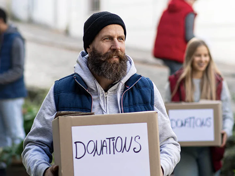 Smiling man holding a cardboard box with a donation sign on the front