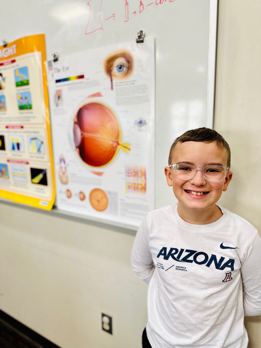 Luke on a field trip standing in front of an eye anatomy poster