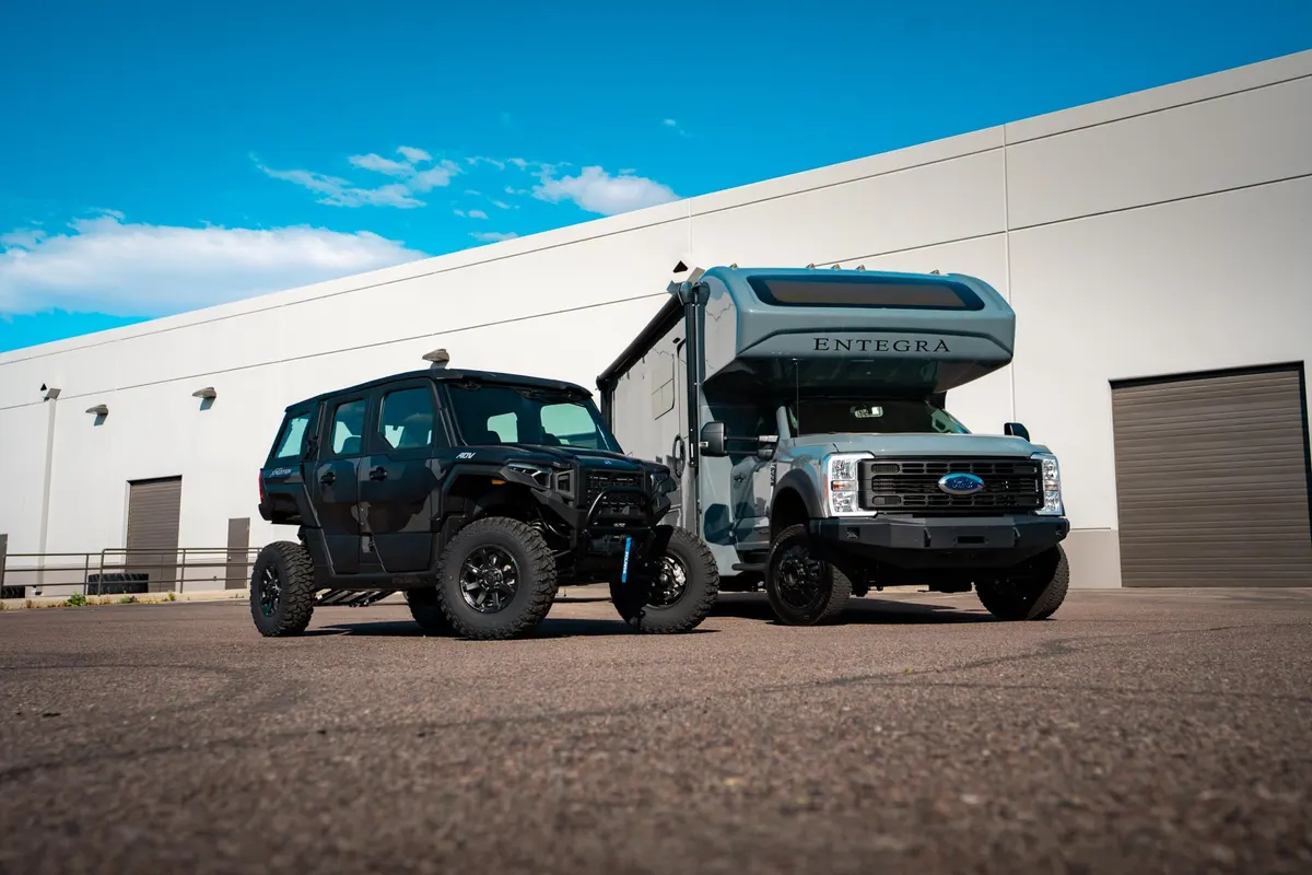 The 2026 Entegra Esteem XL Super C motorhome with the Polaris XPEDITION ADV 5 beside it